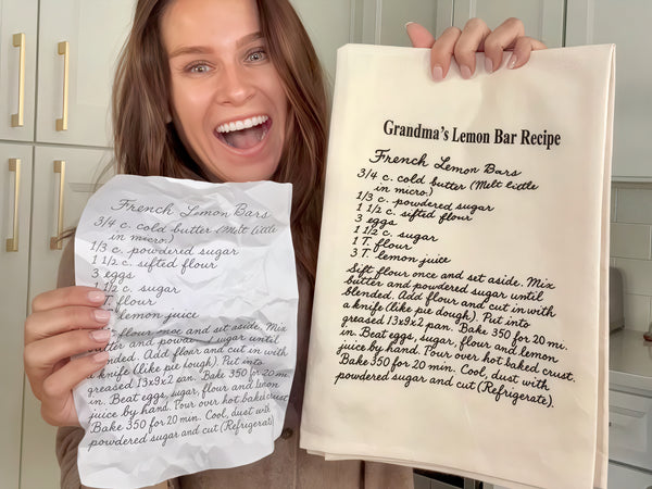 Person holding a handwritten recipe and printed recipe towel in a kitchen. The Printed Gift