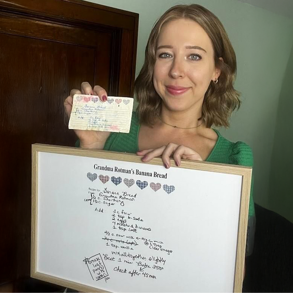 Woman holding a recipe card and a frame with the cleaned up recipe design. 