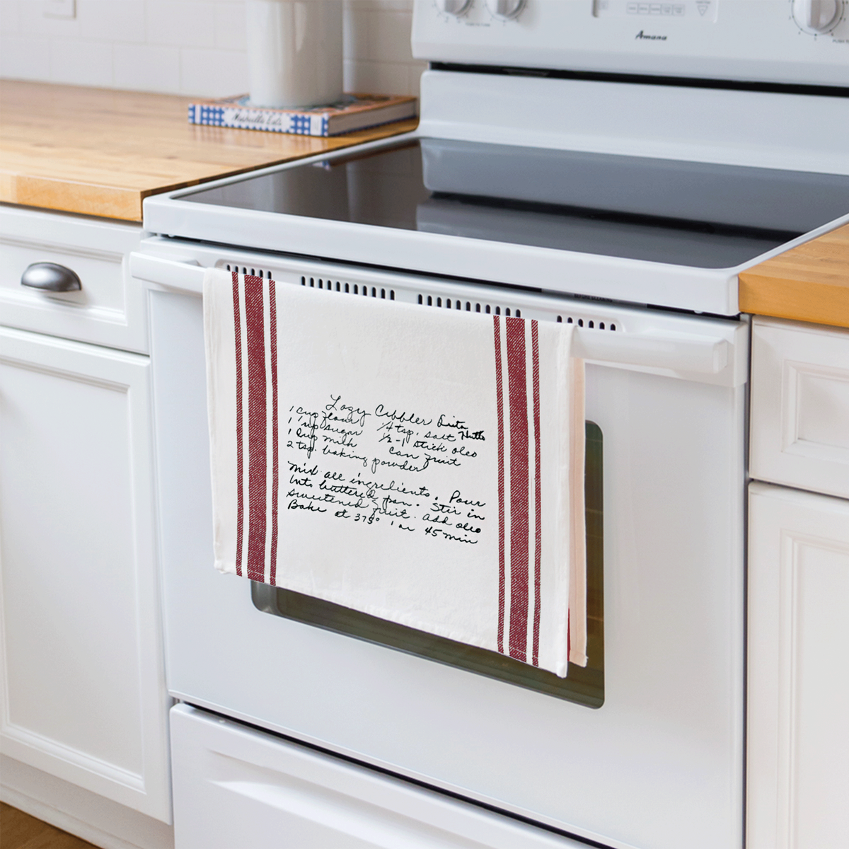 Maroon striped family recipe towel hanging on oven rack in the kitchen